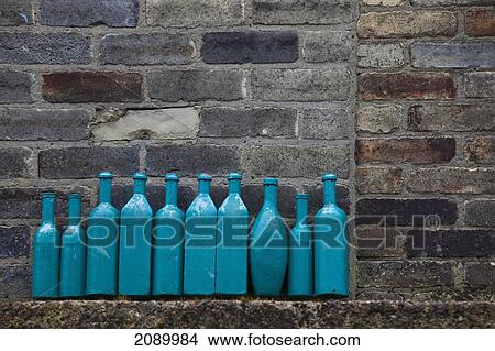 Blue bottles lined up on a ledge against a brick wall; newcastle, northumberland, england View Large Photo Image Picture - Blue bottles lined up on a ledge against a brick wall; newcastle, northumberland, england. Fotosearch