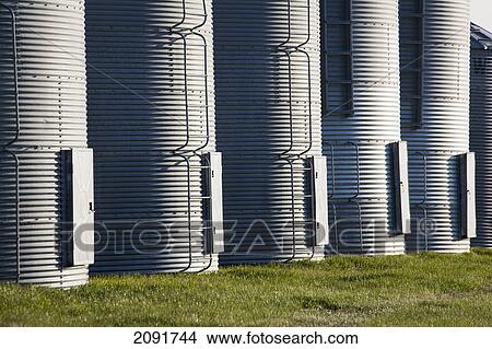 Picture - Close up of a row of metal grain bins with hatch doors; alberta, canada. Fotosearch