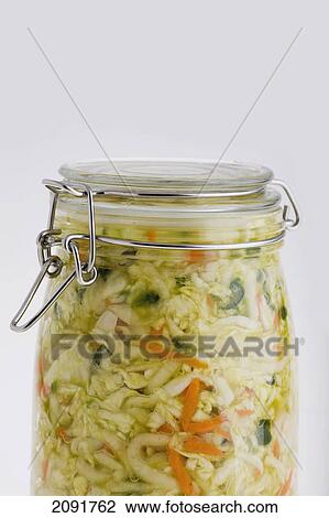Stock Image - Close up of mason canning jar full of sauerkraut with carrots on a white background; calgary, alberta, canada. Fotosearch