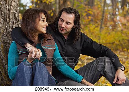 Couple sitting under a tree in autumn; edmonton, alberta, canada View Large Photo Image Stock Photo - Couple sitting under a tree in autumn; edmonton, alberta, canada. Fotosearch