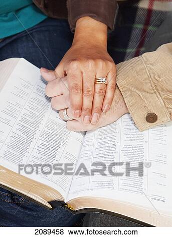 Stock Photo - Couples hands on top of a bible; edmonton, alberta, canada. Fotosearch