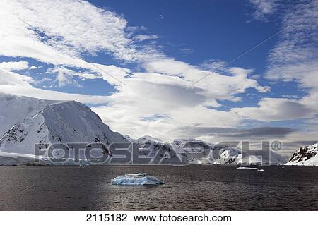 Stock Image - Glaciers snow covered mountains and an iceberg along the coast of the southern ocean; antarctica. Fotosearch