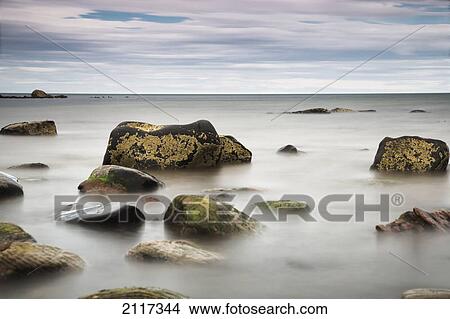 Picture - Large rocks sitting in the water. Fotosearch