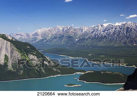 Looking down on emerald blue lakes valley and mountain range from a mountain ridge with blue sky; kananaskis provincial park alberta canada View Large Photo Image Picture - Looking down on emerald blue lakes valley and mountain range from a mountain ridge with blue sky; kananaskis provincial park alberta canada. Fotosearch