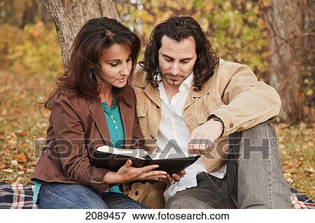 Stock Photo - Married couple reading bible together in a park in autumn; edmonton, alberta, canada. Fotosearch