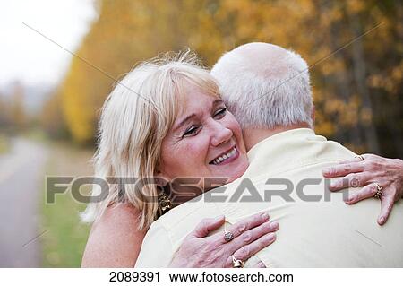 Stock Image - Mature married couple enjoying spending time together in park during fall season; edmonton, alberta, canada. Fotosearch