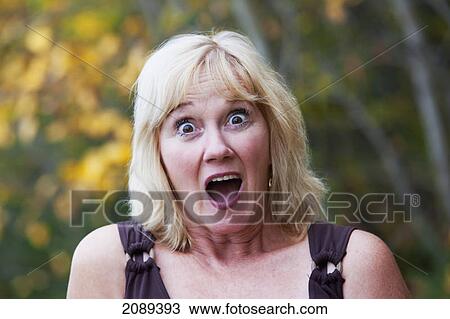 Stock Image - Mature woman surprised in a park with autumn colours; edmonton, alberta, canada. Fotosearch