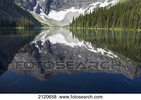Stock Photo - Mountain lake reflection of mountain with some snow; kananaskis provincial park alberta canada. Fotosearch