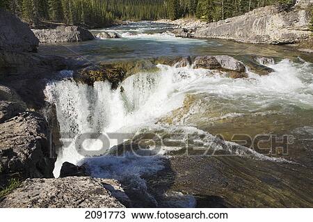 Stock Image - Mountain waterfalls and rushing river with rock cliffs bordering river in kananaskis provincial park; alberta, canada. Fotosearch