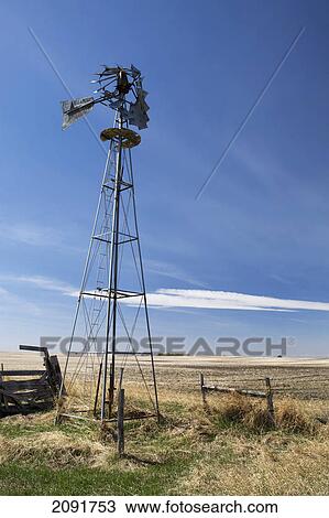 Stock Image - Old windmill in a field with blue sky and cloud; alberta, canada. Fotosearch