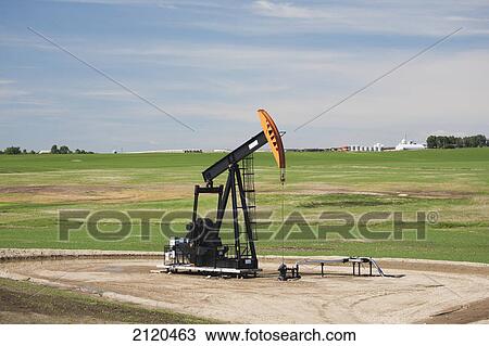 Stock Image - Pumpjack in a field with clouds and blue sky east of airdrie; alberta canada. Fotosearch