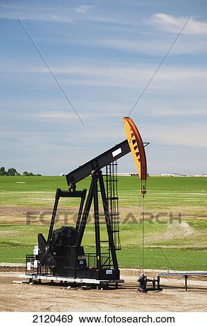 Stock Photo - Pumpjack in a field with clouds and blue sky east of airdrie; alberta canada. Fotosearch