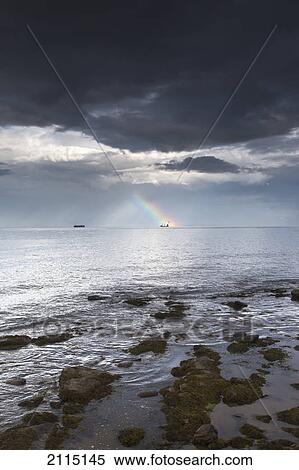 Stock Photography - Rainbow in the distance as seen off the coast; whitley bay tyne and wear england. Fotosearch