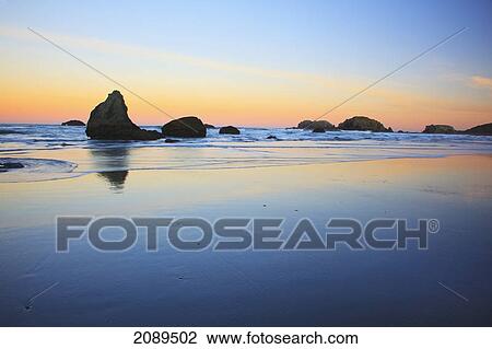 Stock Image - Rock formations reflecting in tide pools at low tide on bandon beach at sunset; oregon, united states of america. Fotosearch