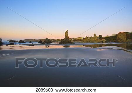Stock Image - Rock formations reflecting in tide pools at low tide on bandon beach at sunset; oregon, united states of america. Fotosearch