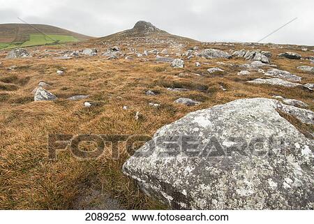 Stock Image - Rock on a rugged landscape under a cloudy sky; ireland. Fotosearch