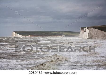 Stock Image - Seven sisters chalk cliffs with big waves; sussex, england. Fotosearch