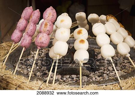 Stock Image - Skewered rice balls cooking around a grill; tokyo, japan. Fotosearch