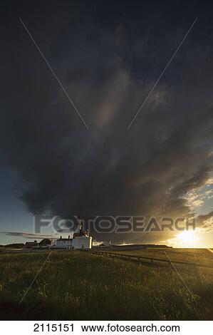 Stock Image - Storm cloud formation over a lighthouse at sunset; south shields tyne and wear england. Fotosearch
