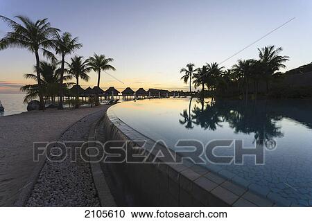 Stock Image - Sunset and palm trees reflecting in a pool at the bora bora nui resort and spa; bora bora island society islands french polynesia south pacific. Fotosearch