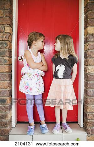Two girls standing in front of a red door making silly expressions at one another; gold coast queensland australia View Large Photo Image Stock Image - Two girls standing in front of a red door making silly expressions at one another; gold coast queensland australia. Fotosearch
