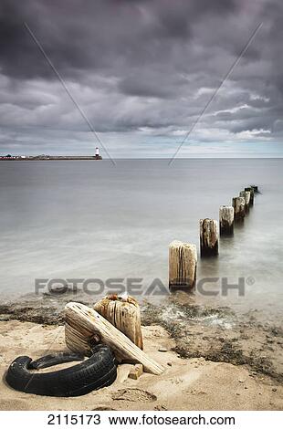 Wooden posts in the water off the coast with a lighthouse in the distance; berwick northumberland england View Large Photo Image Stock Image - Wooden posts in the water off the coast with a lighthouse in the distance; berwick northumberland england. Fotosearch