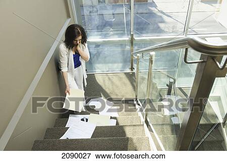 Stock Photo - Young businesswoman drops papers down a set of stairs; edmonton, alberta, canada. Fotosearch