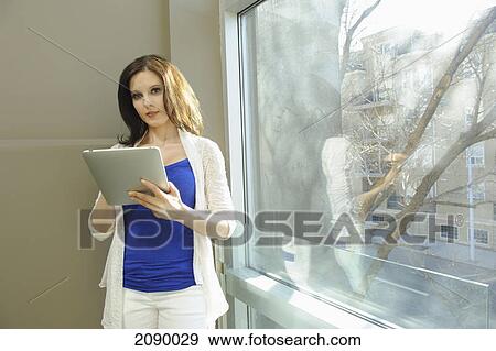 Young businesswoman using a tablet in the hallway of an office building; edmonton, alberta, canada View Large Photo Image Stock Photo - Young businesswoman using a tablet in the hallway of an office building; edmonton, alberta, canada. Fotosearch