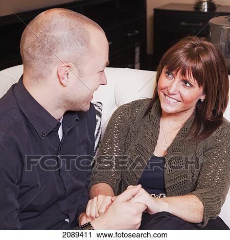 Young married couple holding hands on the couch and talking; edmonton, alberta, canada View Large Photo Image Stock Image - Young married couple holding hands on the couch and talking; edmonton, alberta, canada. Fotosearch