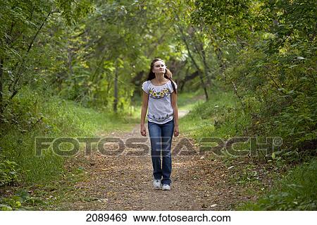 Stock Photo - Young woman walking on a path in a park; edmonton, alberta, canada. Fotosearch
