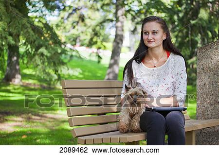 Stock Image - Young woman with her dog and laptop computer in a park; edmonton, alberta, canada. Fotosearch
