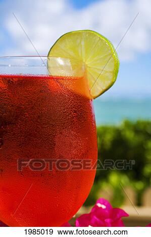 A Bright Red Tropical Cocktail Garnished With Lime In Outdoor Setting. View Large Photo Image Stock Photo - A Bright Red Tropical Cocktail Garnished With Lime In Outdoor Setting.. Fotosearch