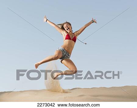 Stock Image - A girl jumping on the beach; tarifa cadiz andalusia spain. Fotosearch