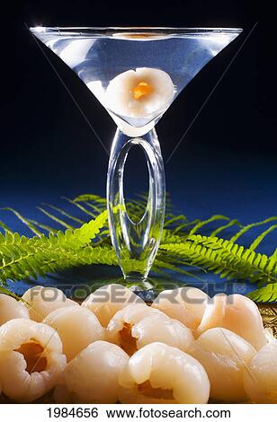 Stock Photograph - A Lychee Martini On A Blue Background With Lychee In Foreground.. Fotosearch
