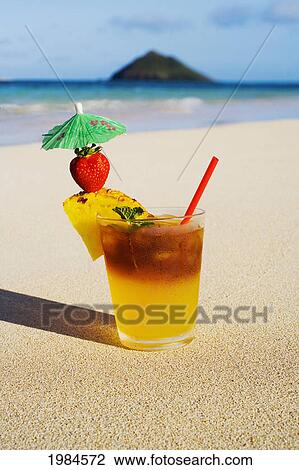 Stock Image - A Mai Tai Garnished With Pinapple And A Strawberry, Sitting In The Sand On The Beach.. Fotosearch