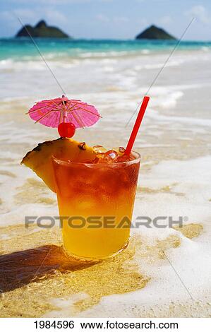 Stock Photograph - A Mai Tai Garnished With Pinapple And A Cherry, Sitting In Shallow Water On The Beach.. Fotosearch