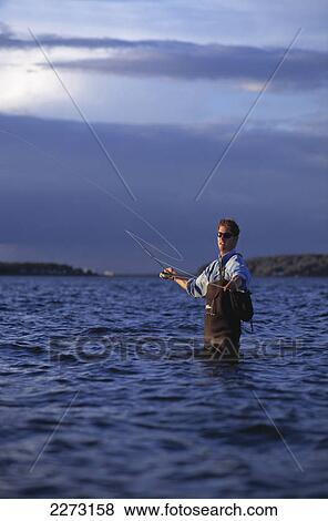 A man fishing while standing in the water; boston massachusetts united states of america View Large Photo Image Stock Photo - A man fishing while standing in the water; boston massachusetts united states of america. Fotosearch