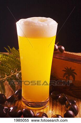 Stock Photography - A Tall Foaming Pint Of Beer In A Tiki Bar Setting.. Fotosearch