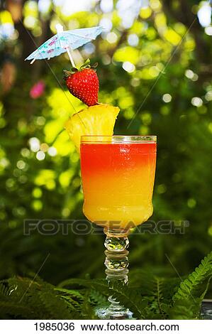 Stock Photograph - A Tequila Sunrise Garnished With Fruit In An Outdoor Setting.. Fotosearch