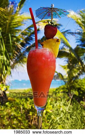 A Tropical Cocktail Garnished With Fruit In An Outdoor Setting. View Large Photo Image Stock Image - A Tropical Cocktail Garnished With Fruit In An Outdoor Setting.. Fotosearch
