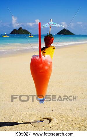 Stock Photo - A Tropical Cocktail On The Beach, Mokulua Islands And Kayakers In Background.. Fotosearch