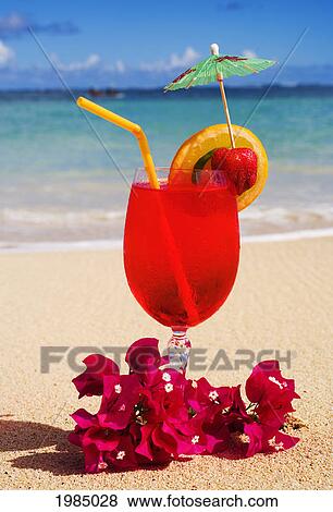 Stock Photo - A Tropical Cocktail On The Beach Garnished With Fruit And Flowers.. Fotosearch