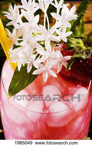 Stock Photo - A Tropical Drink Garnished With Fruit And Flowers.. Fotosearch