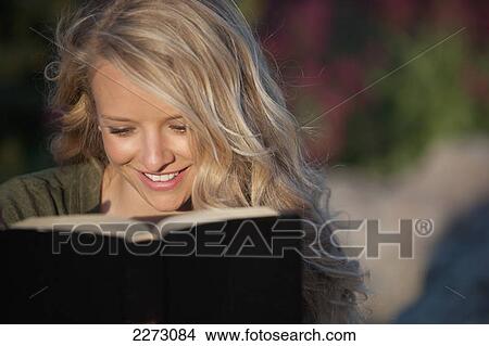 Picture - A woman with long blond hair reading a book; arvada colorado united states of america. Fotosearch