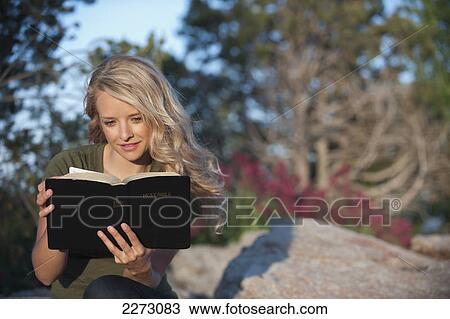 Stock Image - A woman with long blond hair reading the bible; arvada colorado united states of america. Fotosearch