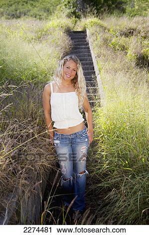 A young woman poses in tall grass with a concrete stairway behind her; hawaii united states of america View Large Photo Image Stock Image - A young woman poses in tall grass with a concrete stairway behind her; hawaii united states of america. Fotosearch
