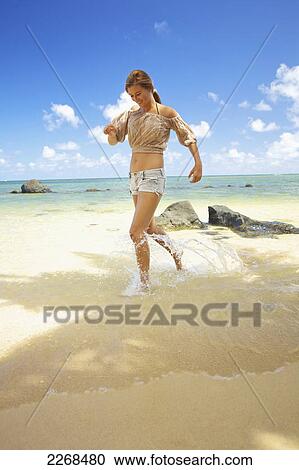 A young woman runs in the shallow water on anini beach; kauai hawaii united states of america View Large Photo Image Stock Image - A young woman runs in the shallow water on anini beach; kauai hawaii united states of america. Fotosearch