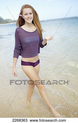 A young woman walks in the shallow water along a beach; kauai hawaii united states of america View Large Photo Image Stock Image - A young woman walks in the shallow water along a beach; kauai hawaii united states of america. Fotosearch