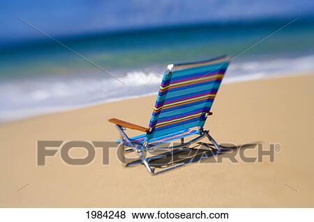 Stock Photo - Brightly Colored Beach Chair On The Sand Near The Ocean.. Fotosearch