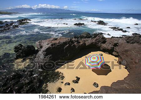 Brightly Colored Beach Umbrella In A Sandy Circle Surrounded By Lava Rock Next To The Ocean. View Large Photo Image Stock Image - Brightly Colored Beach Umbrella In A Sandy Circle Surrounded By Lava Rock Next To The Ocean.. Fotosearch